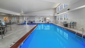 A large indoor swimming pool with clear blue water, surrounded by lounge chairs and a sun terrace. - Residence Inn Champaign (Champaign)