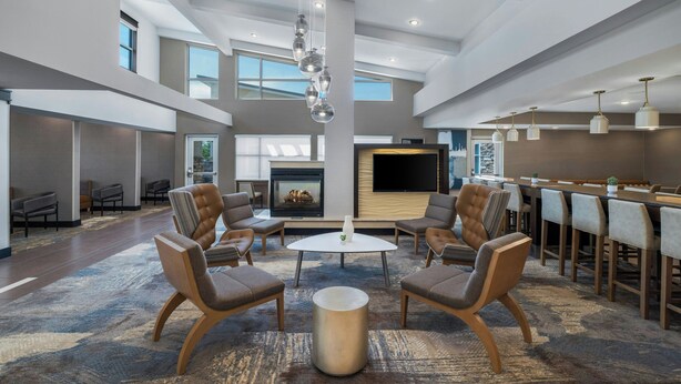 A spacious lobby with a central seating area, a fireplace, and a large TV screen. - Residence Inn Champaign (Champaign)