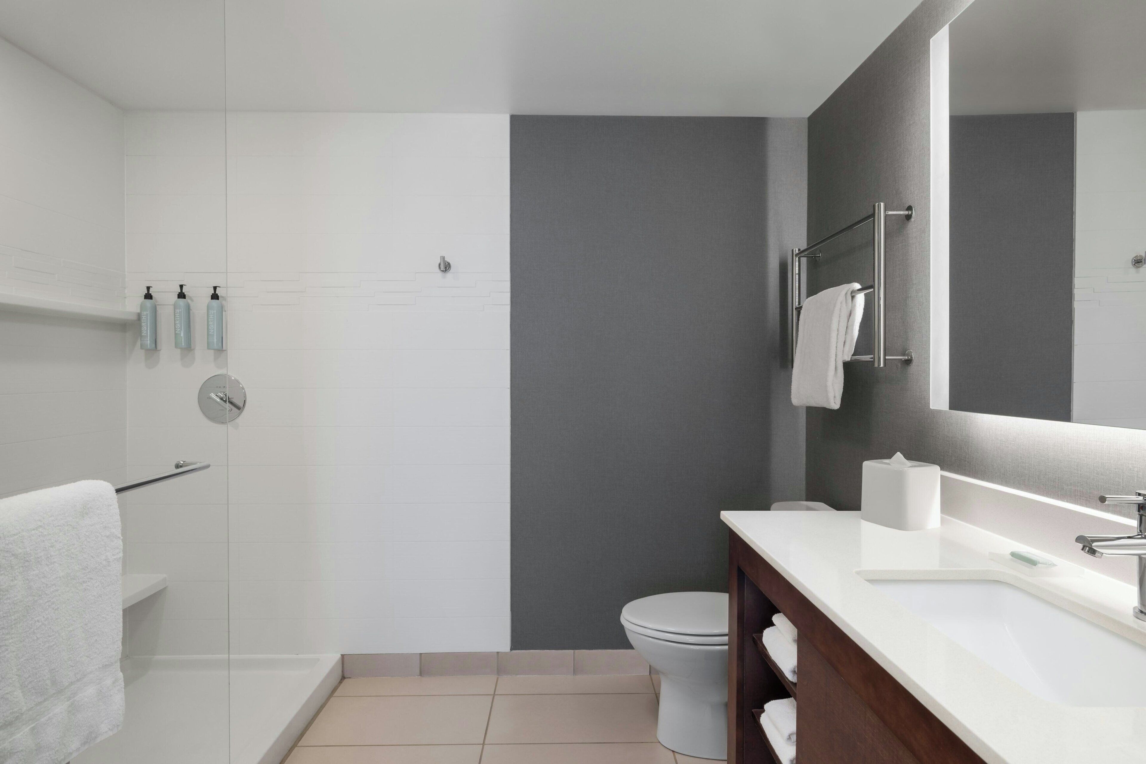 A modern bathroom with a shower, toilet, and sink.