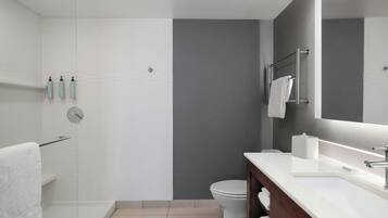 A modern bathroom with a shower, toilet, and sink.