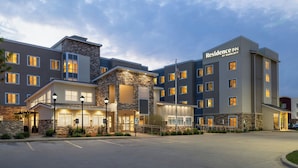 A multi-story hotel with a stone facade, multiple entry points, and a parking lot. - Residence Inn Champaign (Champaign)