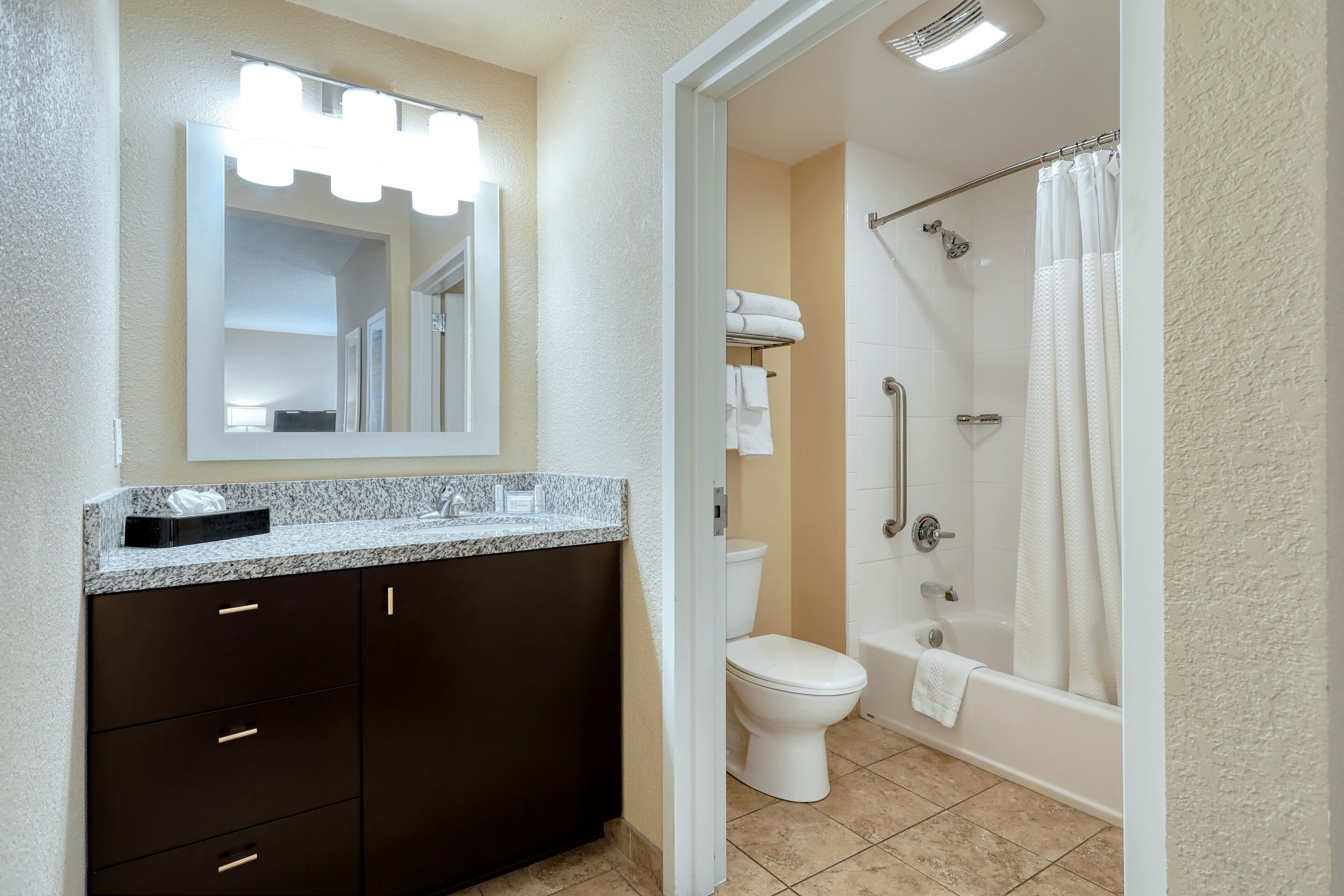 A bathroom with a vanity, mirror, toilet, and shower.