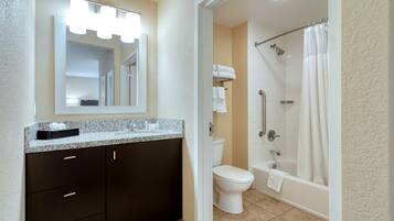 A bathroom with a vanity, mirror, toilet, and shower.