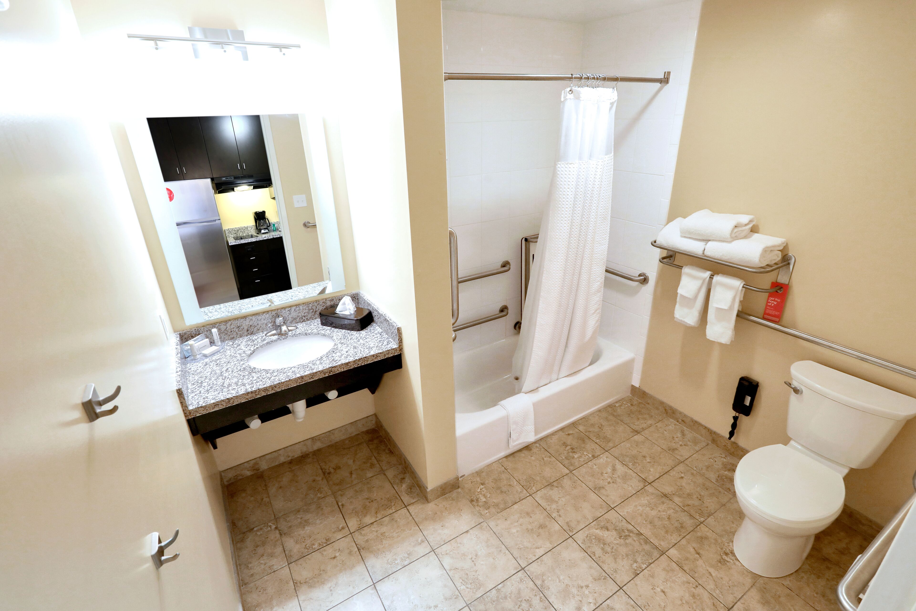 A bathroom with a sink, mirror, bathtub, shower curtain, toilet, and towel rack.