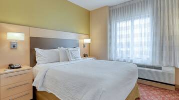 A hotel room with a bed, bedside tables, a telephone, and a window with curtains.