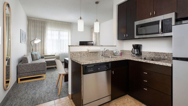 A modern kitchen with dark cabinetry, stainless steel appliances, and a granite countertop. - TownePlace Suites York (York)