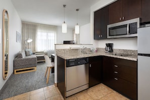 A modern kitchen with dark cabinetry, stainless steel appliances, and a granite countertop. - TownePlace Suites York (York)