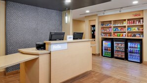 A reception area with a 'Hello' sign, a counter with a coffee machine, and refrigerated beverage dispensers. - TownePlace Suites York (York)