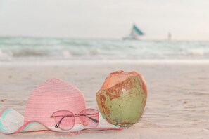 A beach scene with a straw hat, sunglasses, and a coconut on the sand. - Eurotel Boracay (Boracay Island)
