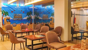 A gaming area with tables, chairs, and a mural depicting a gaming theme. - Eurotel Boracay (Boracay Island)