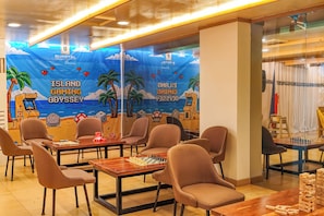 A gaming area with tables, chairs, and a mural depicting a gaming theme.