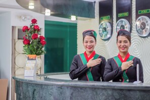 Two receptionists at a hotel reception desk with a clock and a vase of red roses. - Eurotel Boracay (Boracay Island)