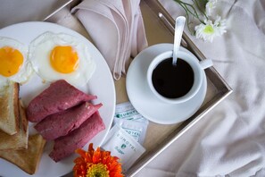 A tray with breakfast items including eggs, ham, toast, and coffee, along with a napkin and a flower. - Eurotel Boracay (Boracay Island)