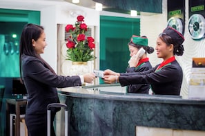 A reception desk with a vase of red roses, a clock, and a counter.