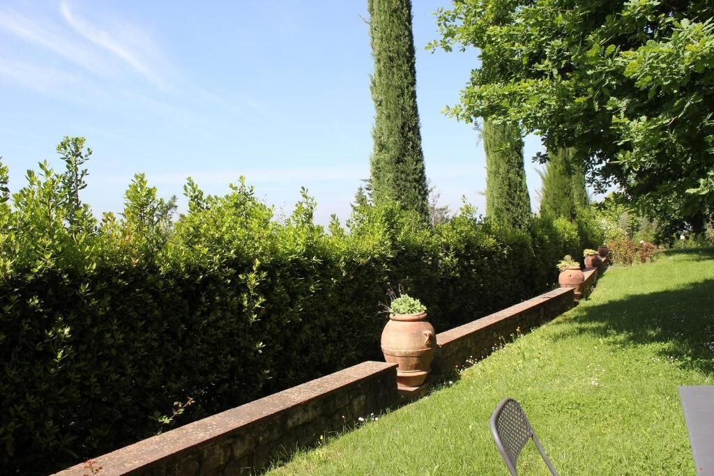 A garden with a brick wall, potted plants, and a chair.