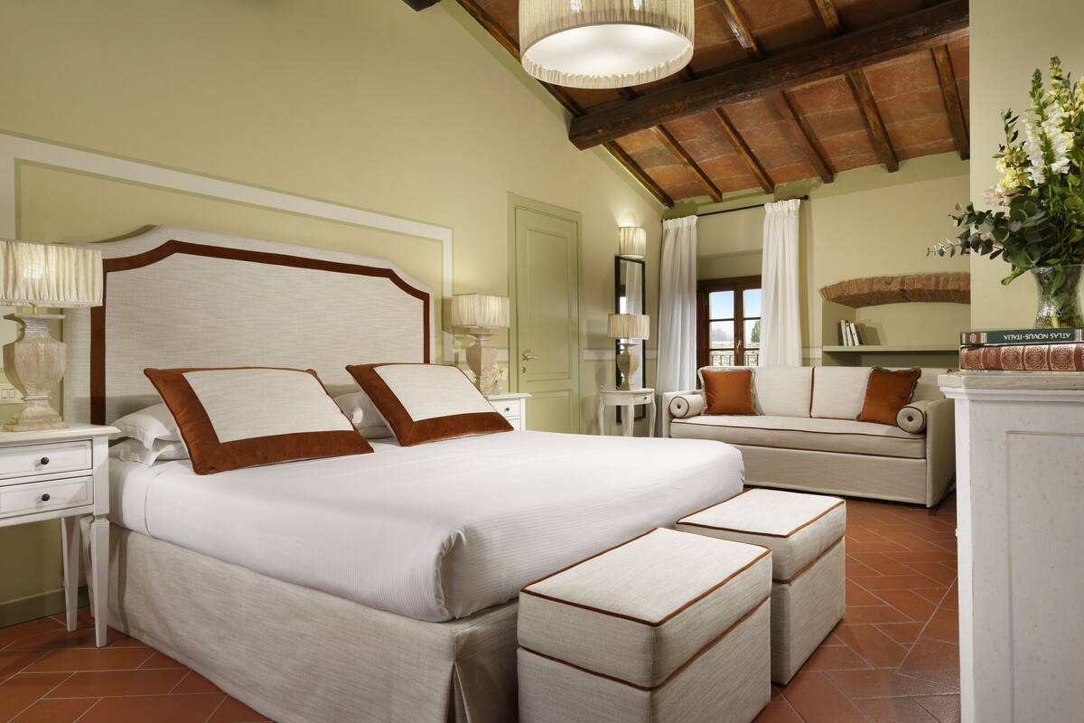 Une chambre à coucher avec un grand lit, des tables de chevet, un canapé et un miroir.