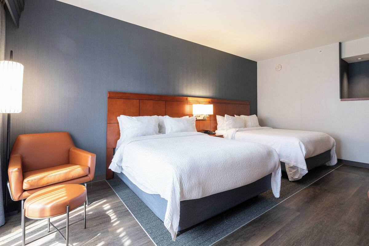 A hotel room with a large bed, two bedside tables, a chair, and a TV mounted on the wall.