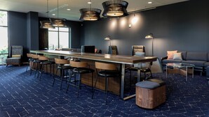 A modern conference room with a long table, bar stools, and a sofa. - Courtyard Cincinnati Midtown/Rookwood (Cincinnati)