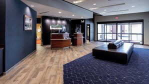 A modern lobby with a reception desk, a seating area, and large windows providing a view of the outside. - Courtyard Cincinnati Midtown/Rookwood (Cincinnati)
