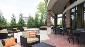 An outdoor patio area with wicker furniture, a round table, and a fire pit. - Courtyard Cincinnati Midtown/Rookwood (Cincinnati)