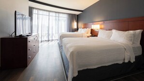 A hotel room with two beds, a TV, a dresser, and a large window with curtains. - Courtyard Cincinnati Midtown/Rookwood (Cincinnati)