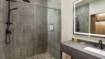 A bathroom with a shower, a sink, and a mirror.