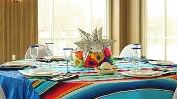 Una mesa de comedor dispuesta con platos, vasos y un centro de mesa decorativo.