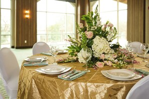 A table set for dining with a gold tablecloth, white plates, and a floral centerpiece.