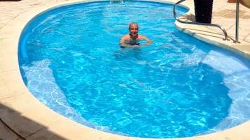 Una piscina al aire libre, sillones reclinables de piscina