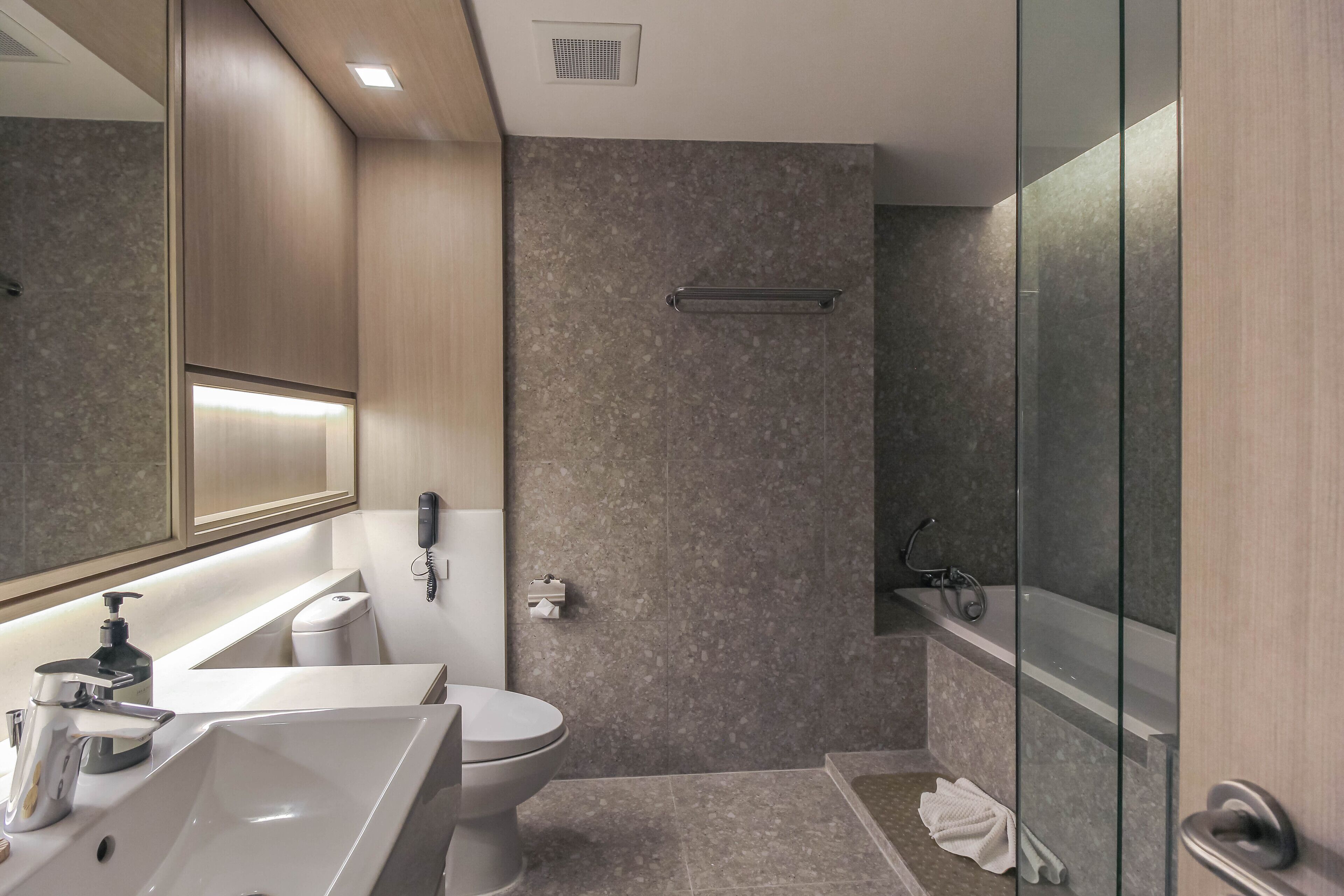 Une salle de bain moderne équipée d’un lavabo, de toilettes et d’une zone douche.