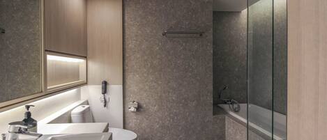Une salle de bain moderne équipée d’un lavabo, de toilettes et d’une zone douche.