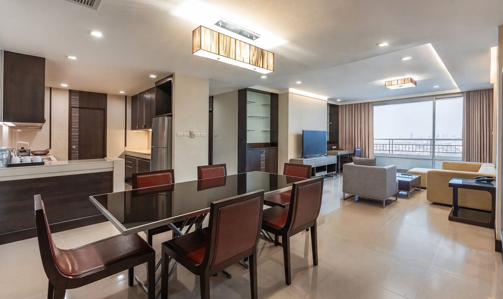 Une chambre d’hôtel moderne dotée d’un coin repas, d’un salon et d’un balcon offrant une vue sur la ville.