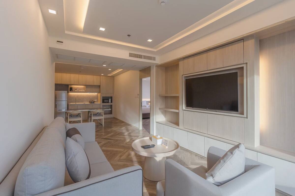A modern living room with a sofa, a coffee table, and a TV mounted on the wall.