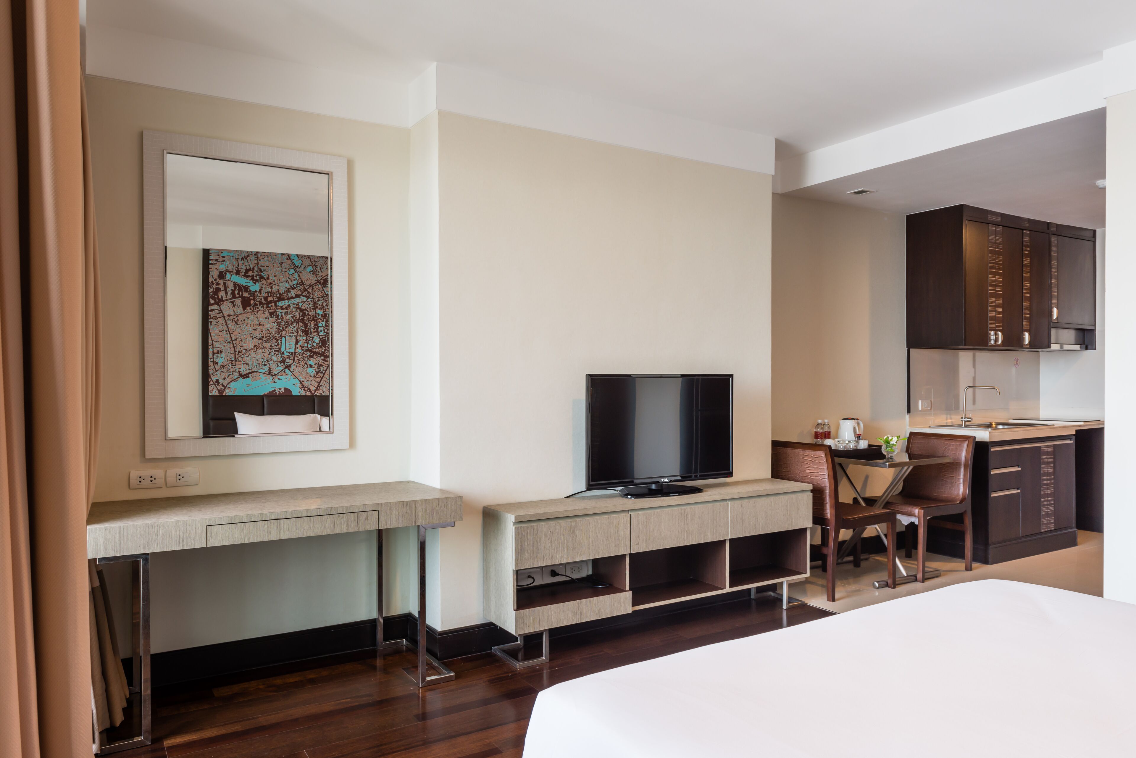 Een moderne hotelkamer met een groot bed, een bureau met een flatscreen-televisie, een kleine kitchenette en een zithoek.