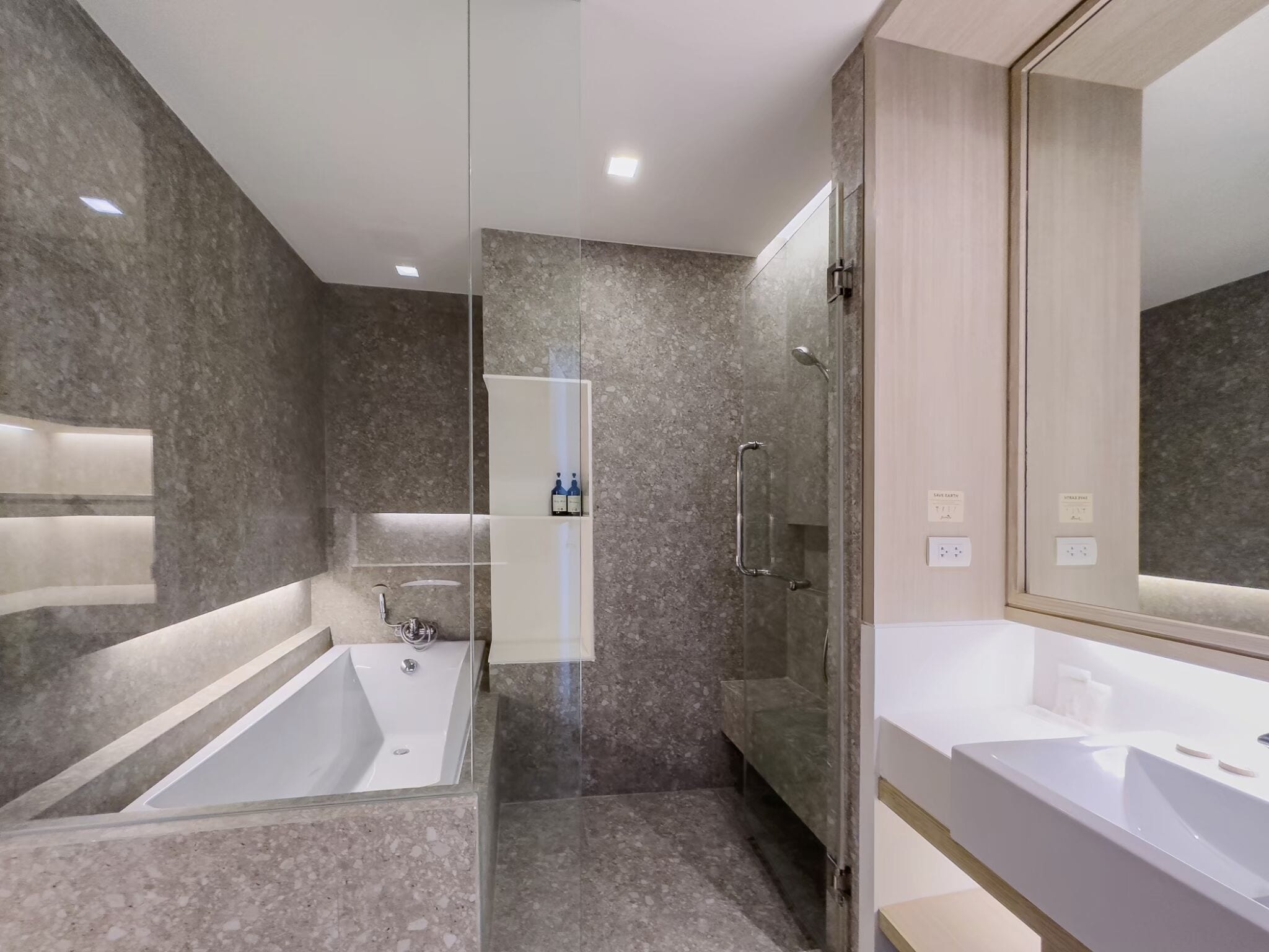 Ein modernes Badezimmer mit einer Badewanne, einer gläsernen Duschkabine und einem großen Spiegel.