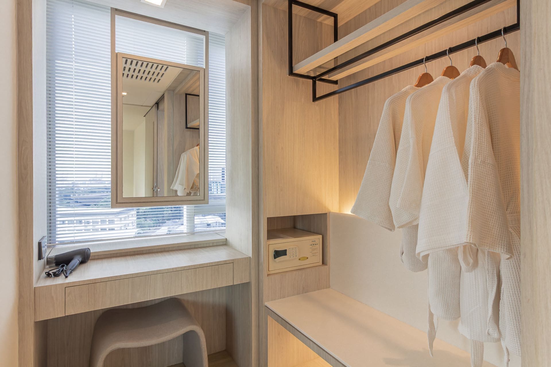 A modern bathroom with a wooden vanity, a mirror, a towel rack with towels, and a small stool.