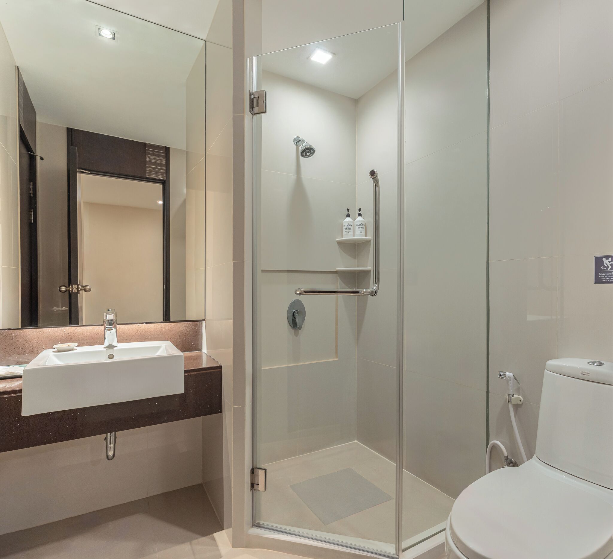 A modern bathroom with a glass-enclosed shower, a sink with a marble countertop, and a toilet.