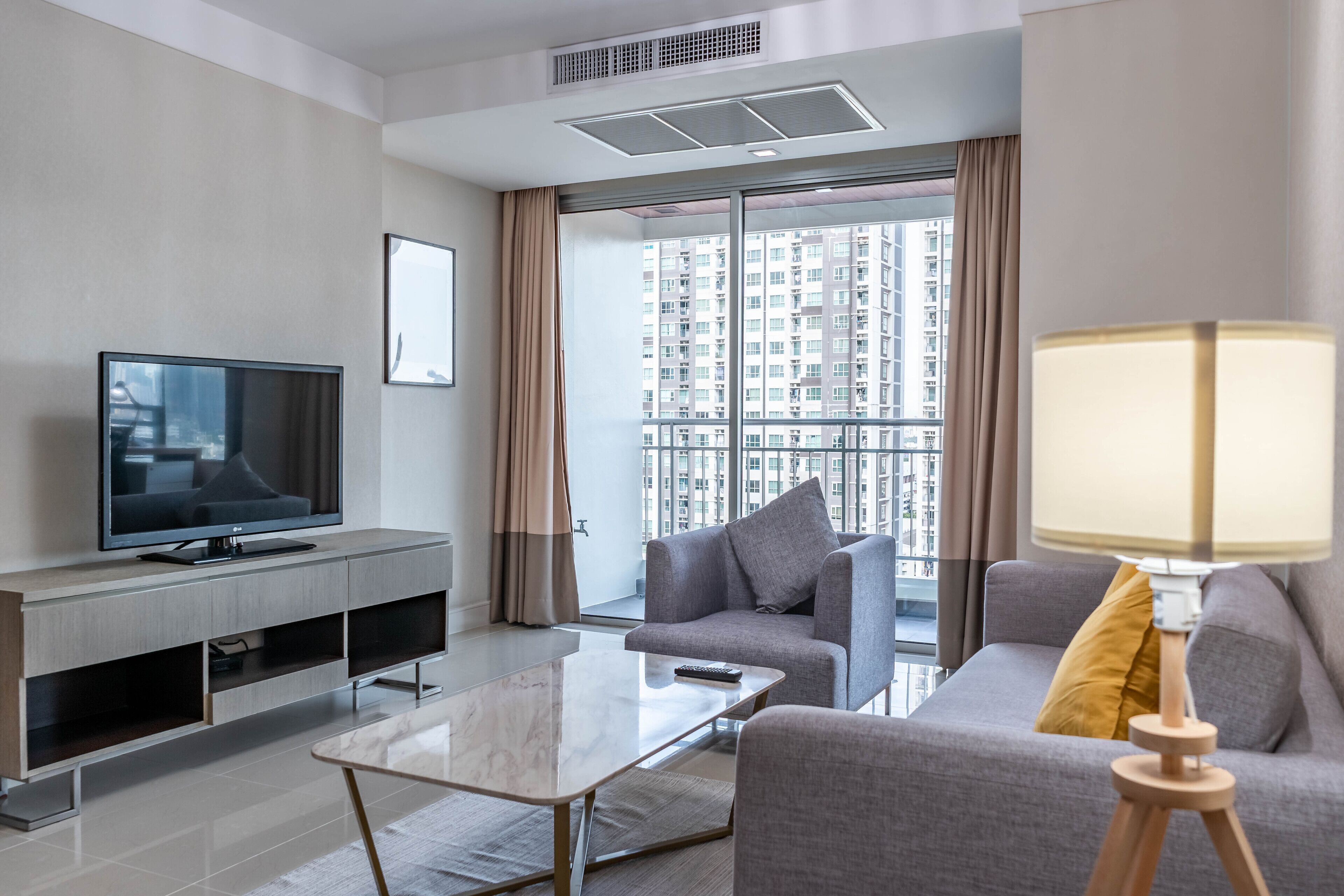 A modern living room with a flat-screen TV, a sofa, a coffee table, and a lamp.