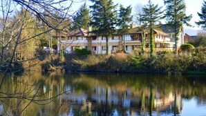 A lakeside hotel with a reflection in the water, surrounded by trees and a clear sky. - Killarney View House B&B (Killarney)