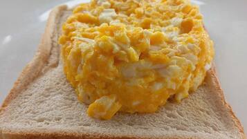 Una tostada con huevos revueltos sobre un plato blanco.