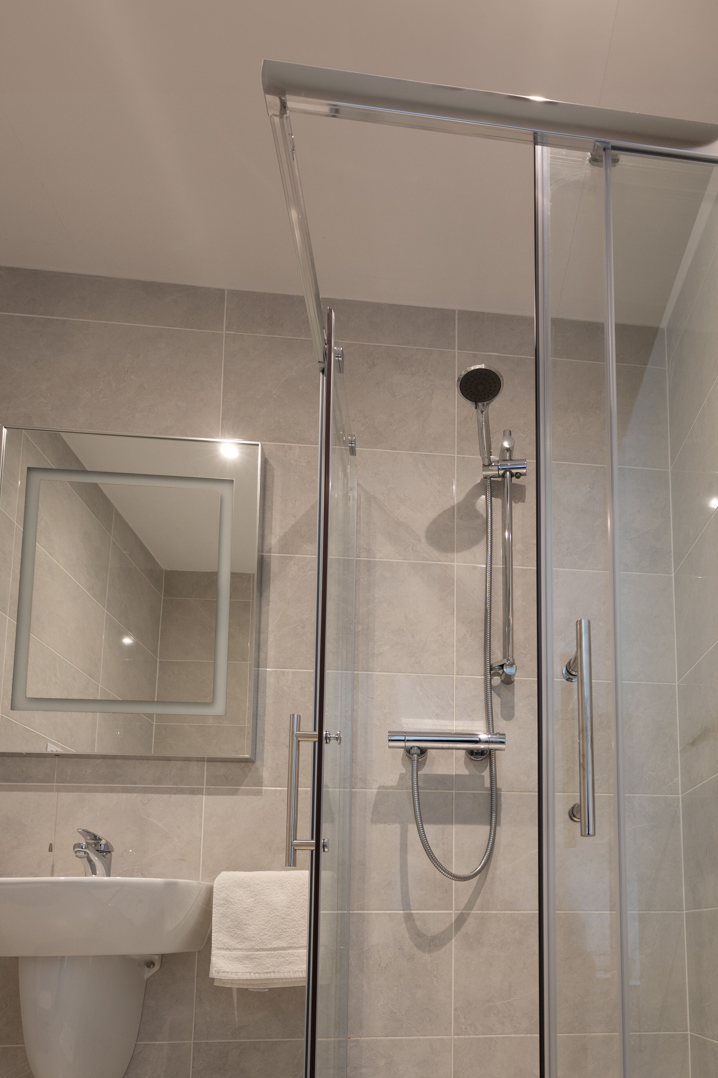 Une salle de bain moderne avec une douche à parois de verre, un lavabo et un miroir.