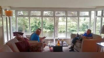 A living room with large windows, a sofa, a coffee table, and a lamp.