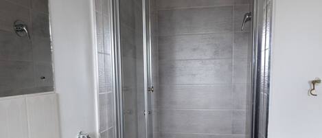 A bathroom with a shower, sink, and mirror.