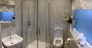 Une salle de bain moderne avec une douche à parois de verre, un lavabo, des toilettes et un miroir.
