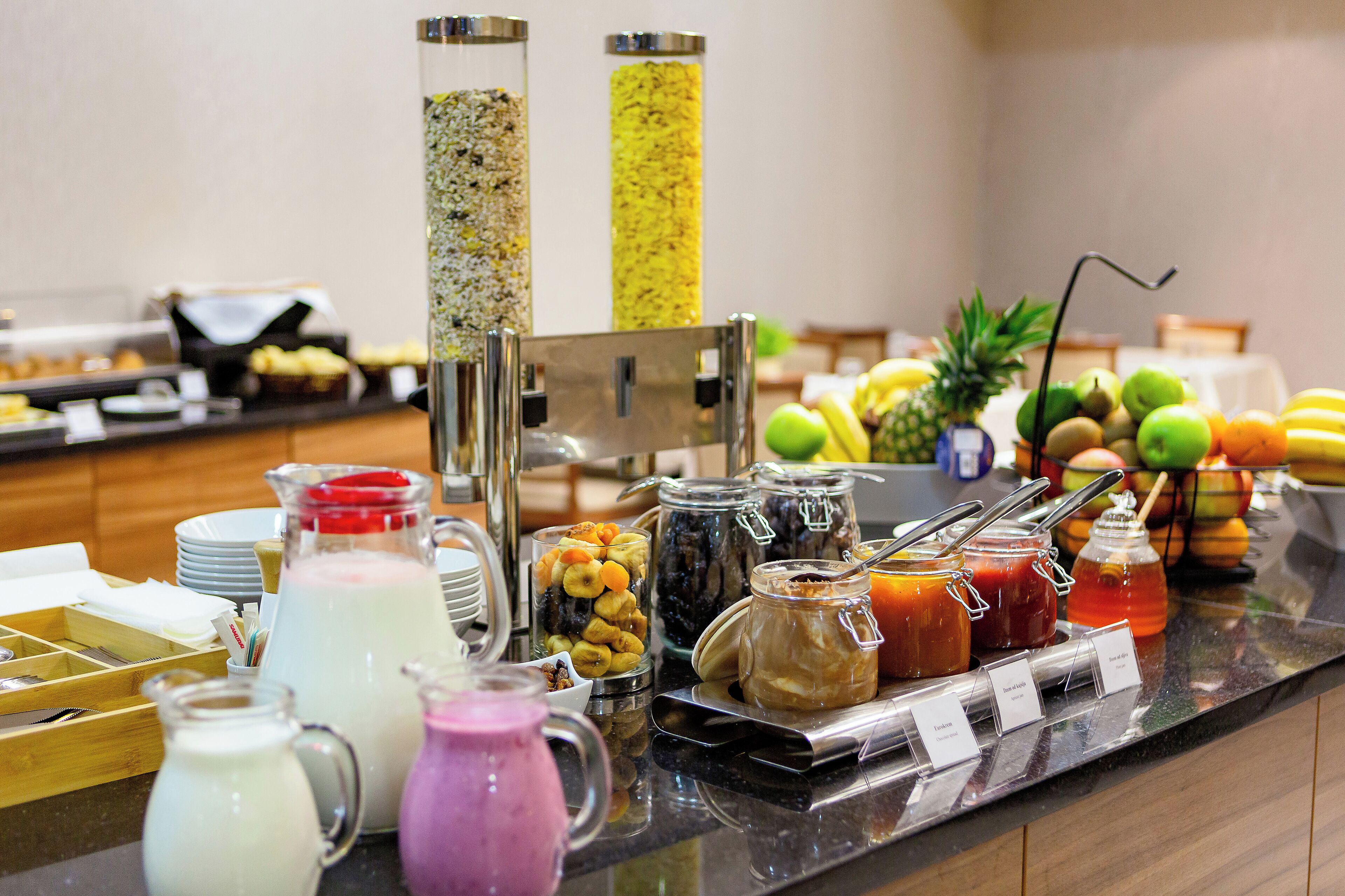 A buffet with various food items and beverages, including fruits, juices, and condiments.