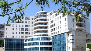 A modern multi-story building with large windows and balconies, surrounded by greenery. - KINGS PARK HOTEL (Podgorica)