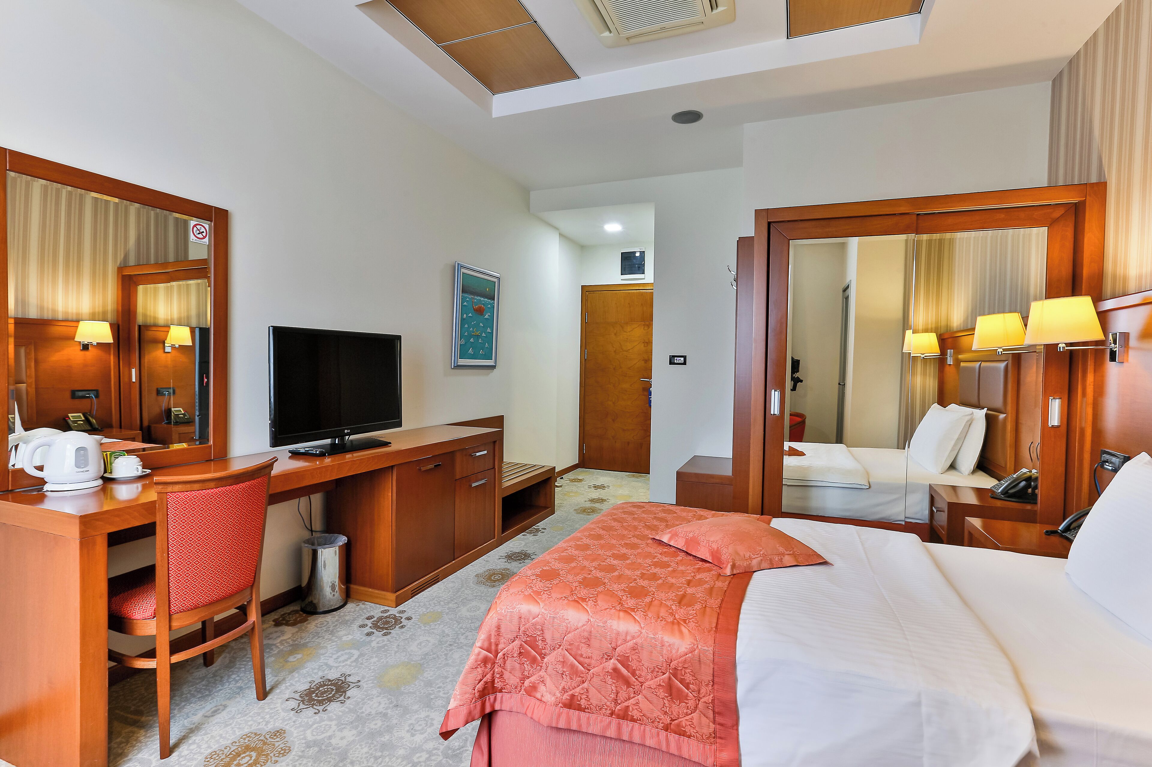 Une chambre d’hôtel équipée d’un lit, d’un bureau, d’une chaise, d’une télévision et d’un miroir.