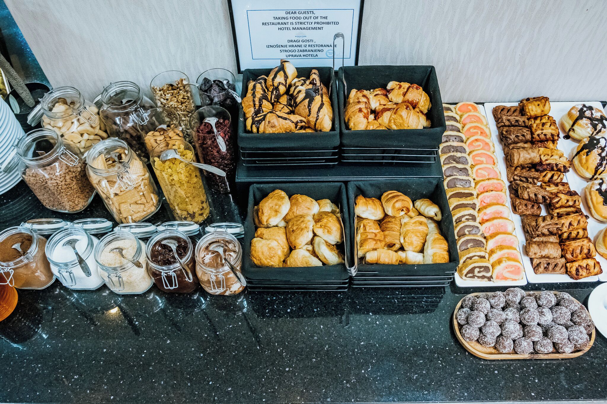 A buffet spread with various pastries, desserts, and condiments.