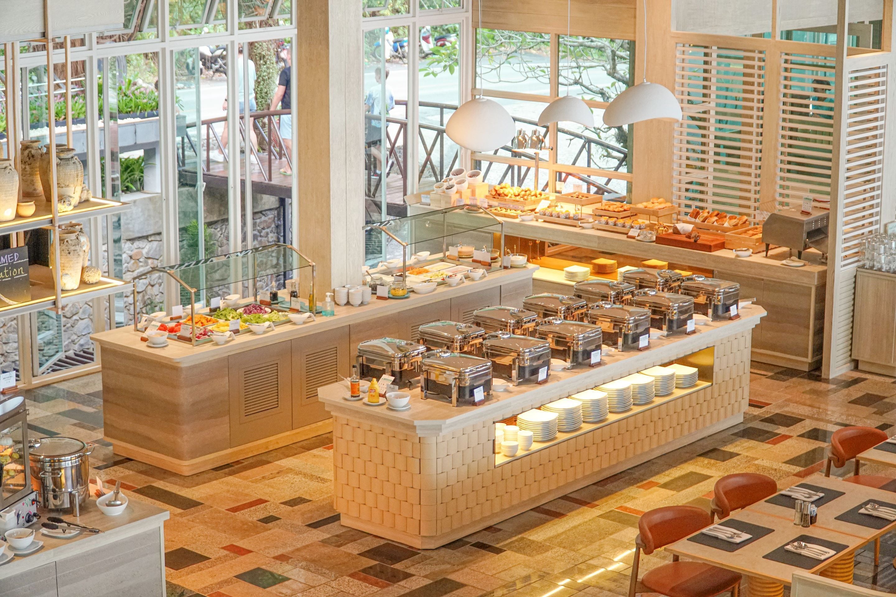 A buffet with various food items and a seating area with tables and chairs.