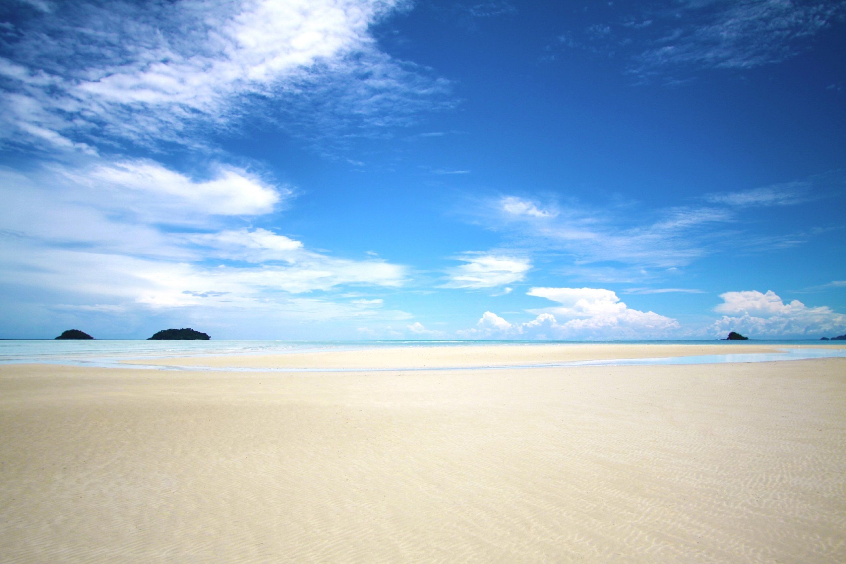 Une plage avec un ciel dégagé et une mer calme.